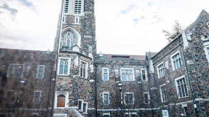 Alumni Memorial Hall reflected in a fountain on campus